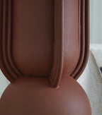 Brick-red metal lamp base with fluted columns, close-up detail