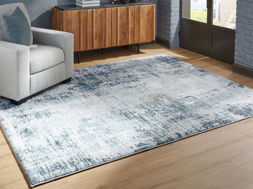 Blue and white abstract area rug with faded texture, stretched flat on wood floor