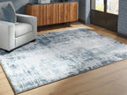 Blue and white abstract area rug with faded texture, stretched flat on wood floor