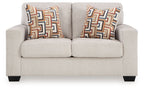 Light beige loveseat with two patterned throw pillows and low, squared arms.