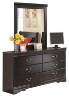 Black dresser with attached mirror and drawer fronts with metal handles.