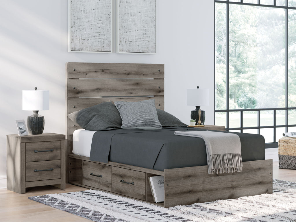 Dark gray storage bed with slatted headboard and two drawers beneath, made with bedding
