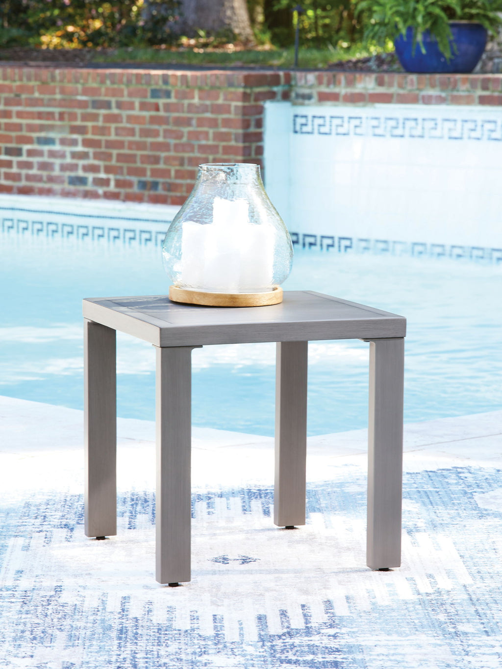 Gray square end table with flat top and four legs; vase on tabletop
