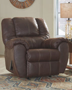 Brown leather rocker recliner with curved arms, tufted back, and extended footrest