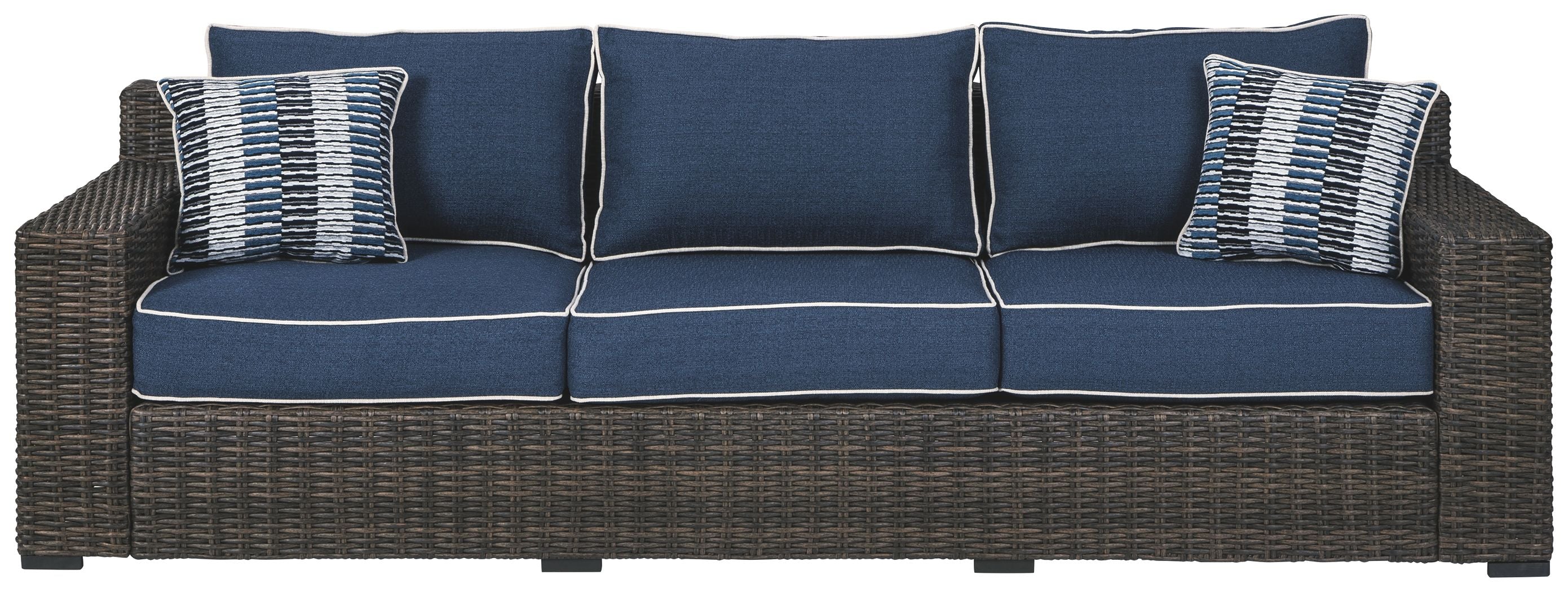 Three-seat brown wicker sofa with blue back cushions and two striped throw pillows