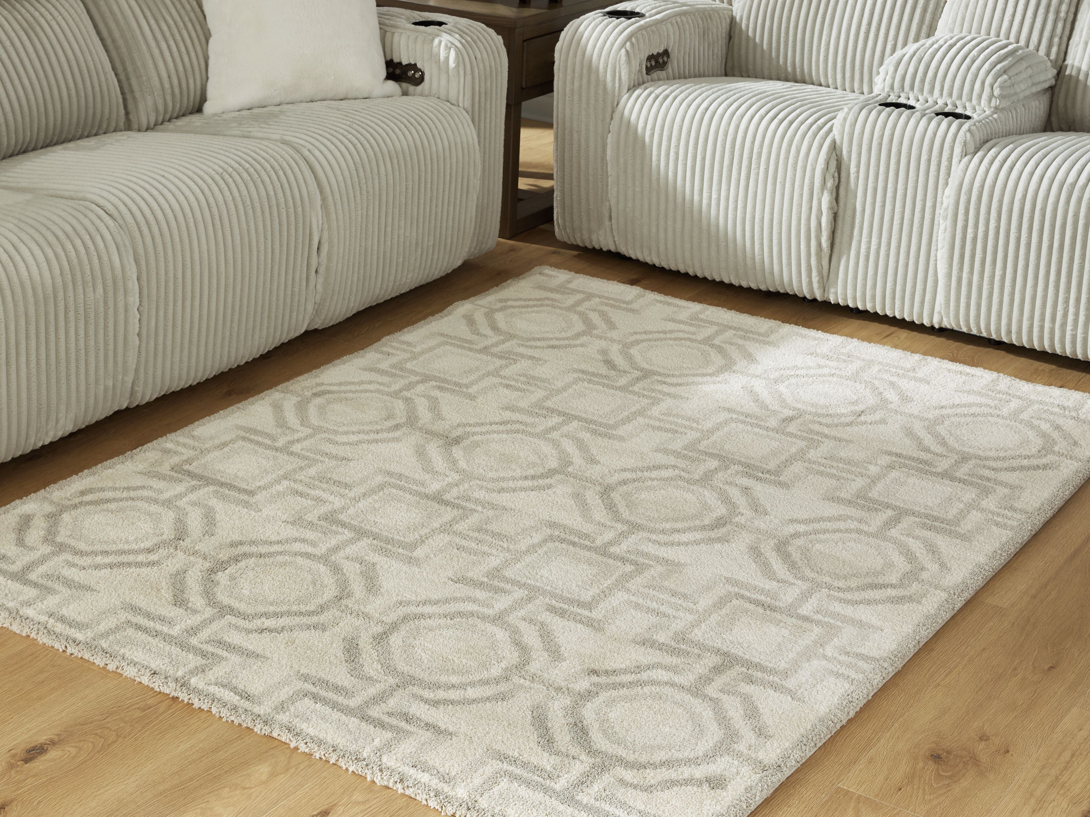 Beige area rug with geometric pattern, centered on light wood flooring
