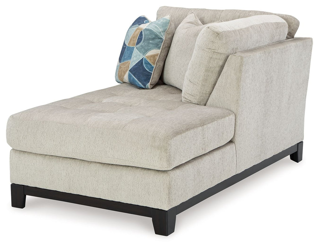 Stone corner chaise with wide seat, tufted back, dark legs, and geometric accent pillow