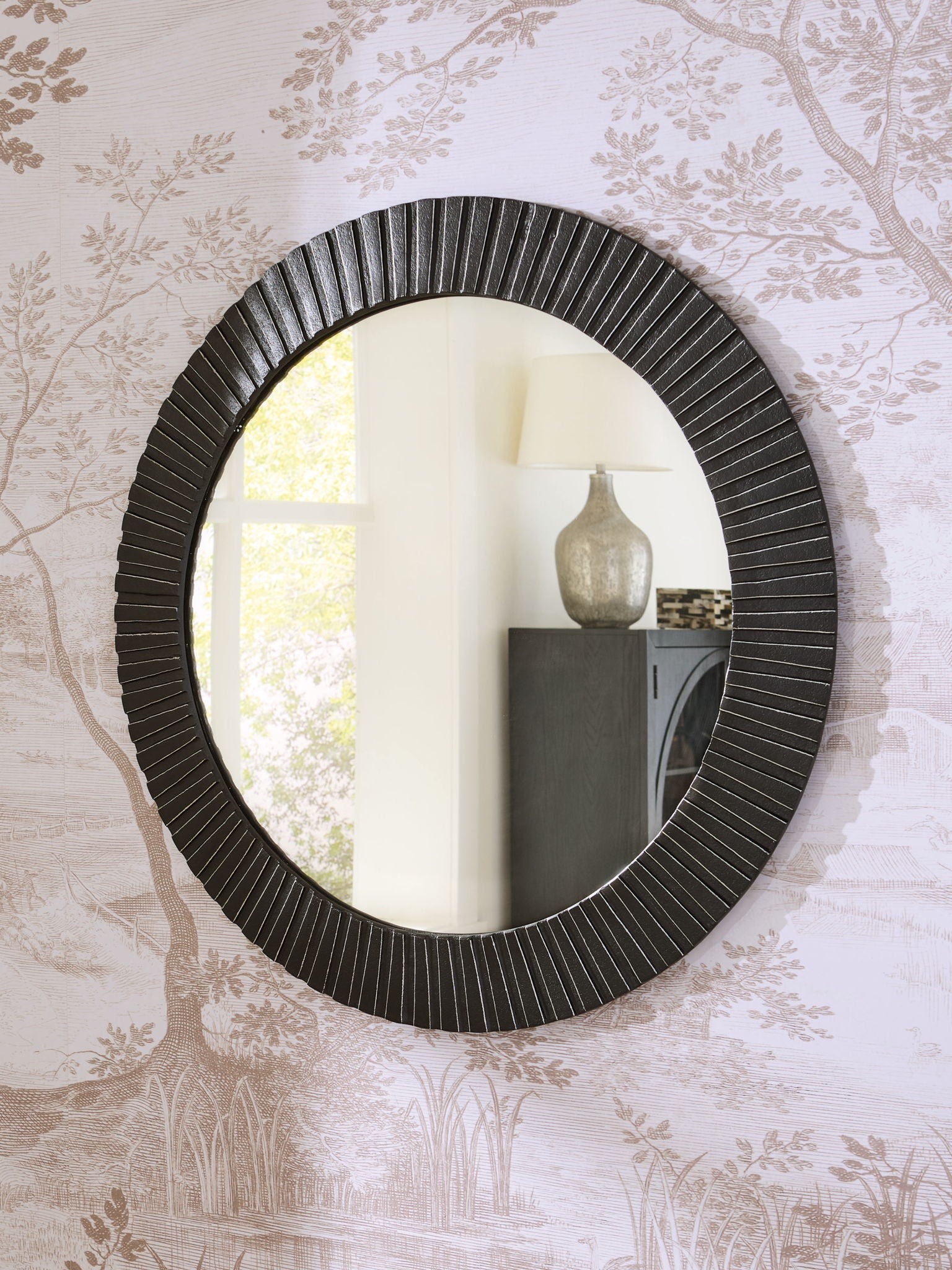 Black round accent mirror with ribbed frame and reflective glass, wall-mounted