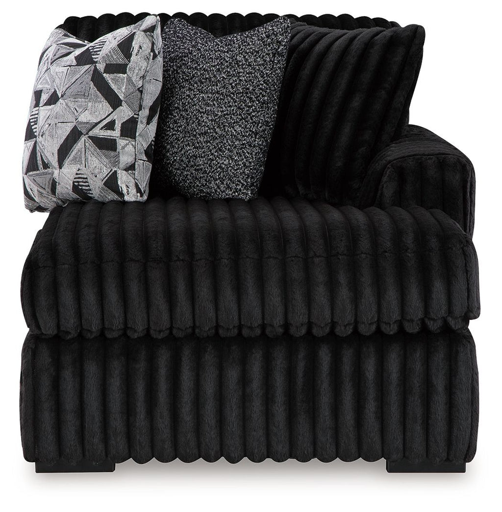 Black ribbed corner chaise with thick seat cushions and patterned lumbar pillow