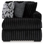 Black ribbed corner chaise with thick seat cushions and patterned lumbar pillow