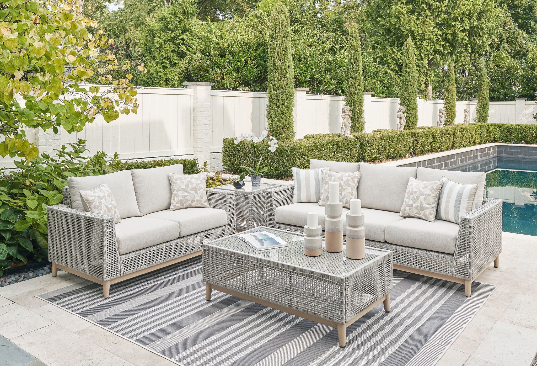 Gray woven outdoor lounge set with two sofas, cushions, and coffee table