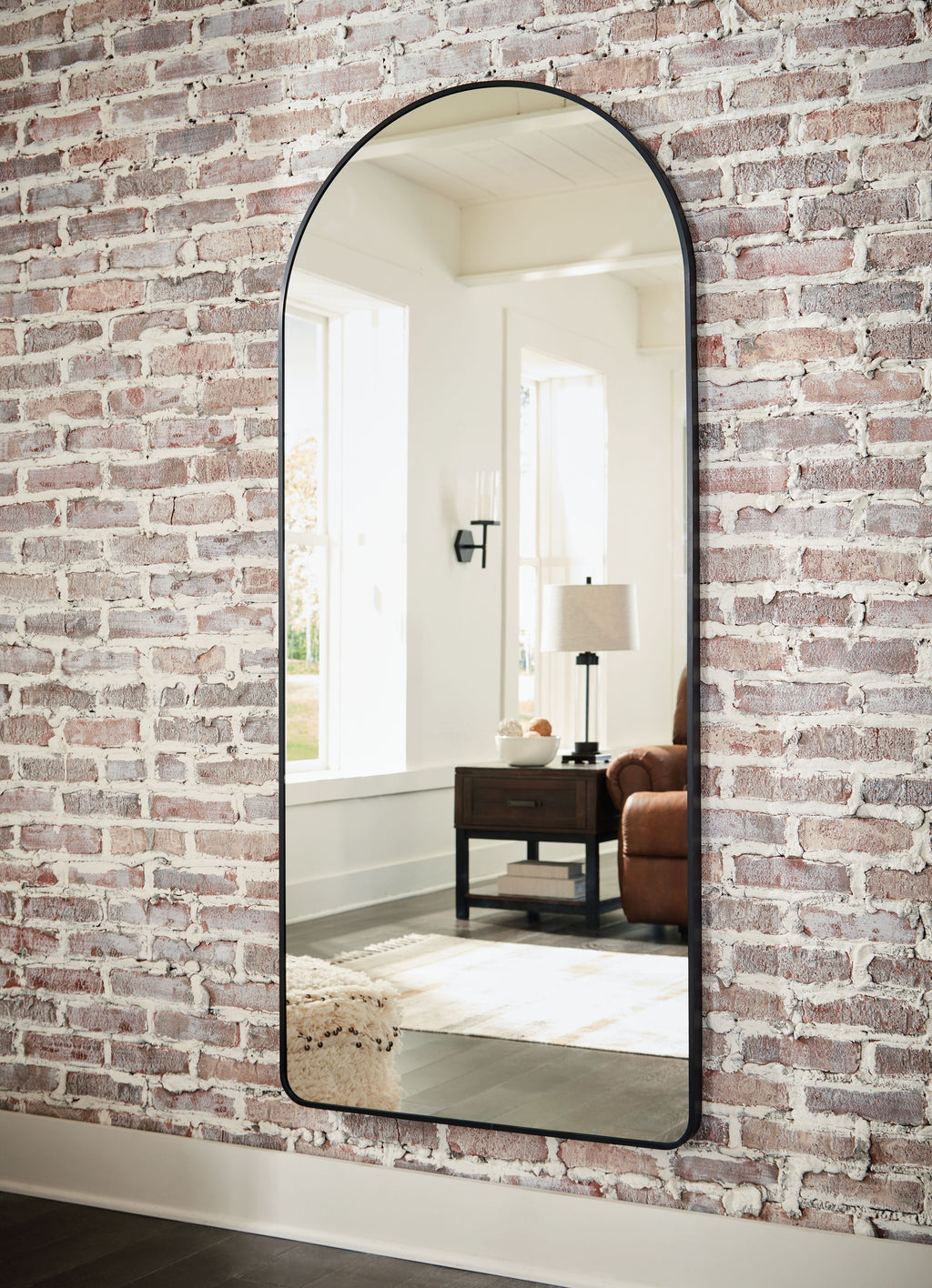 Sethall black arched floor mirror with thin frame, viewed at an angle