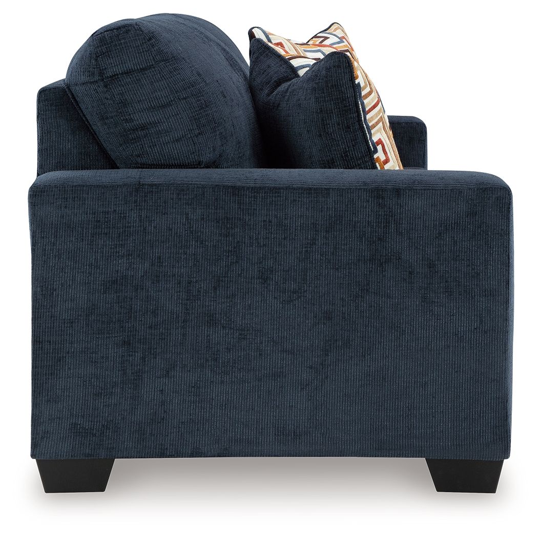 Ink blue sofa sleeper side profile with two back cushions and patterned throw pillow.