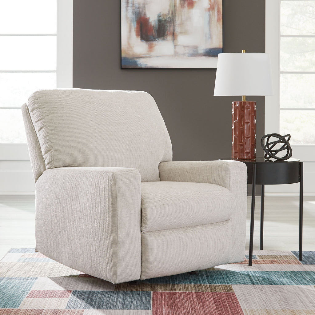 Rocker recliner chair in light beige upholstered fabric with angled back and padded arms.