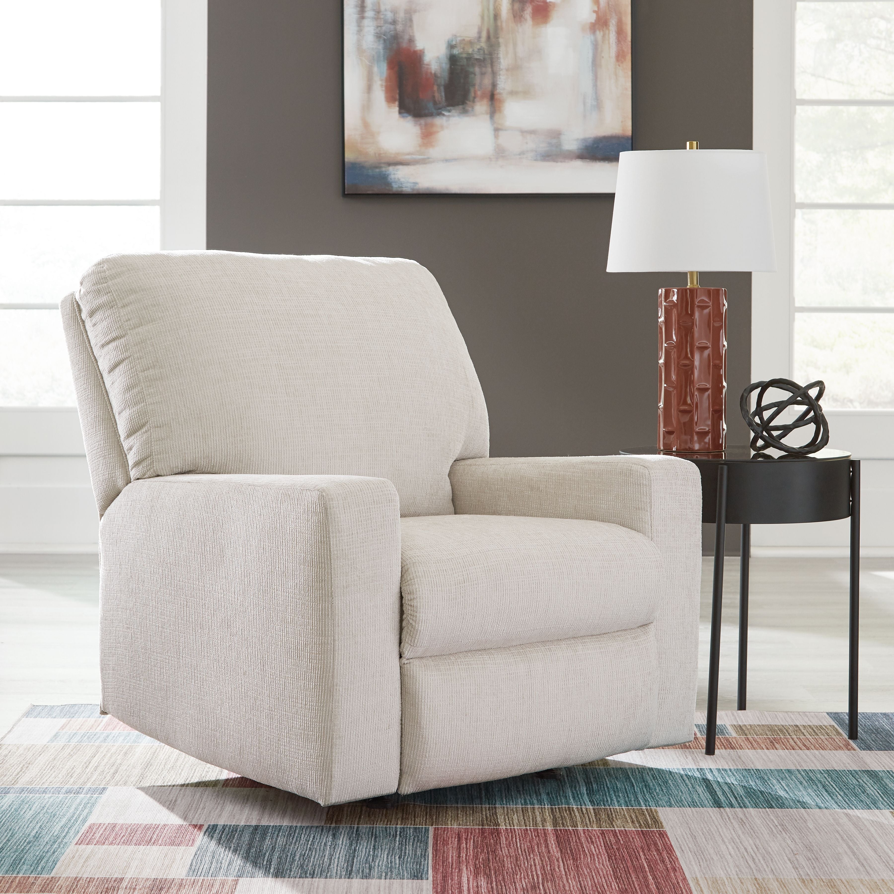 Rocker recliner chair in light beige upholstered fabric with angled back and padded arms.