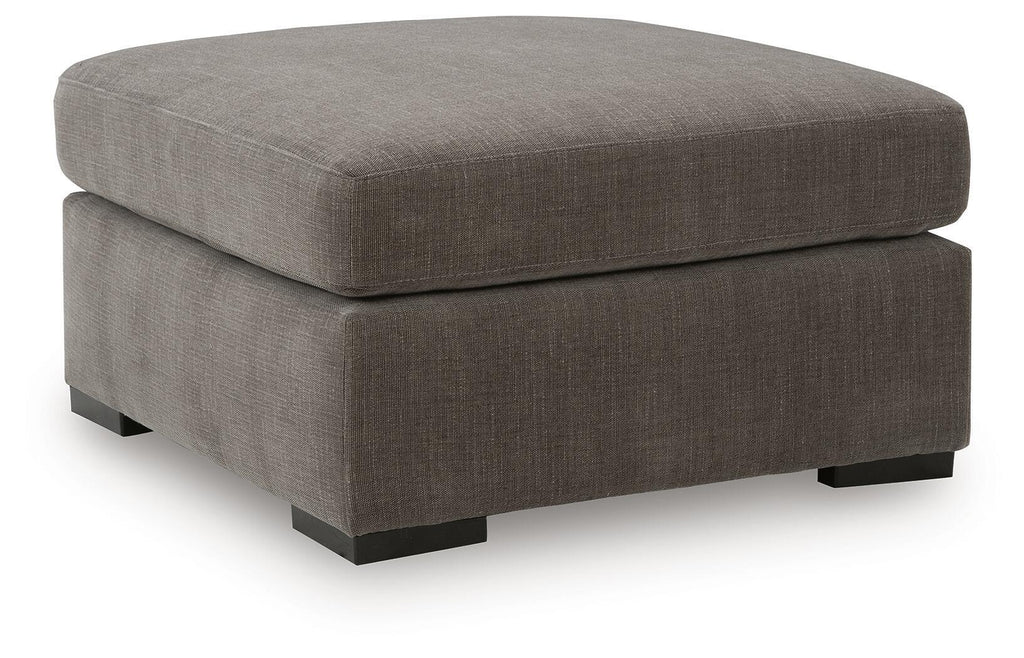 Gray upholstered accent ottoman with cushioned top and square base with block legs