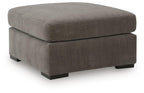 Gray upholstered accent ottoman with cushioned top and square base with block legs