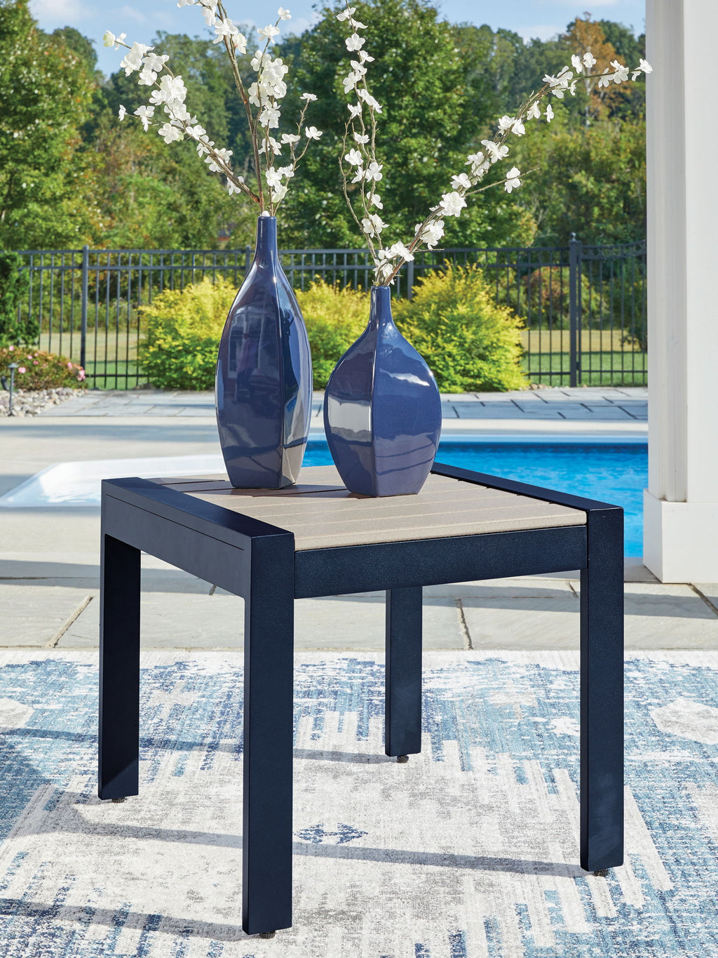 Blue rectangular cocktail table with slatted beige top, dark frame, and vase decor