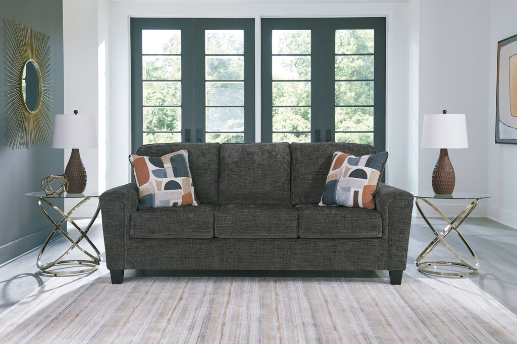 Dark gray sofa with three seat cushions and patterned throw pillows