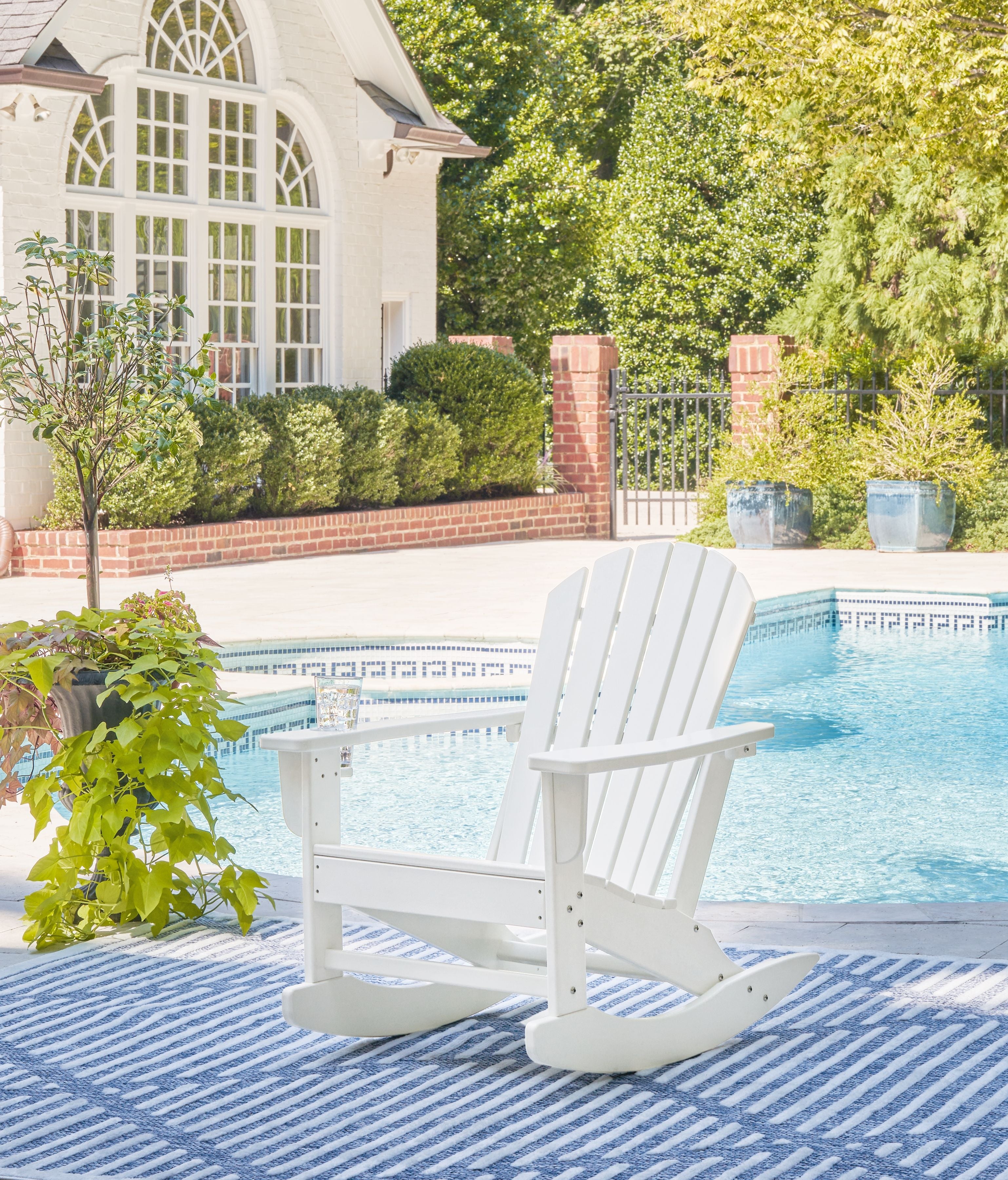 White Adirondack rocking chair with slatted back and armrests, shown on outdoor deck.