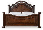 Dark brown poster bed front view with ornate arched headboard, paneled rails, 2 pillows