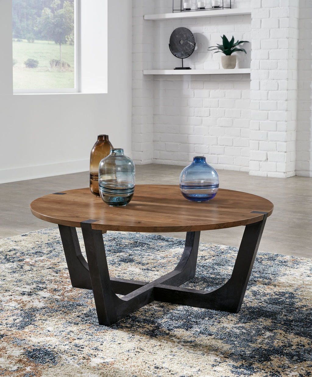 Round cocktail table with brown wood top and black metal base, bottles