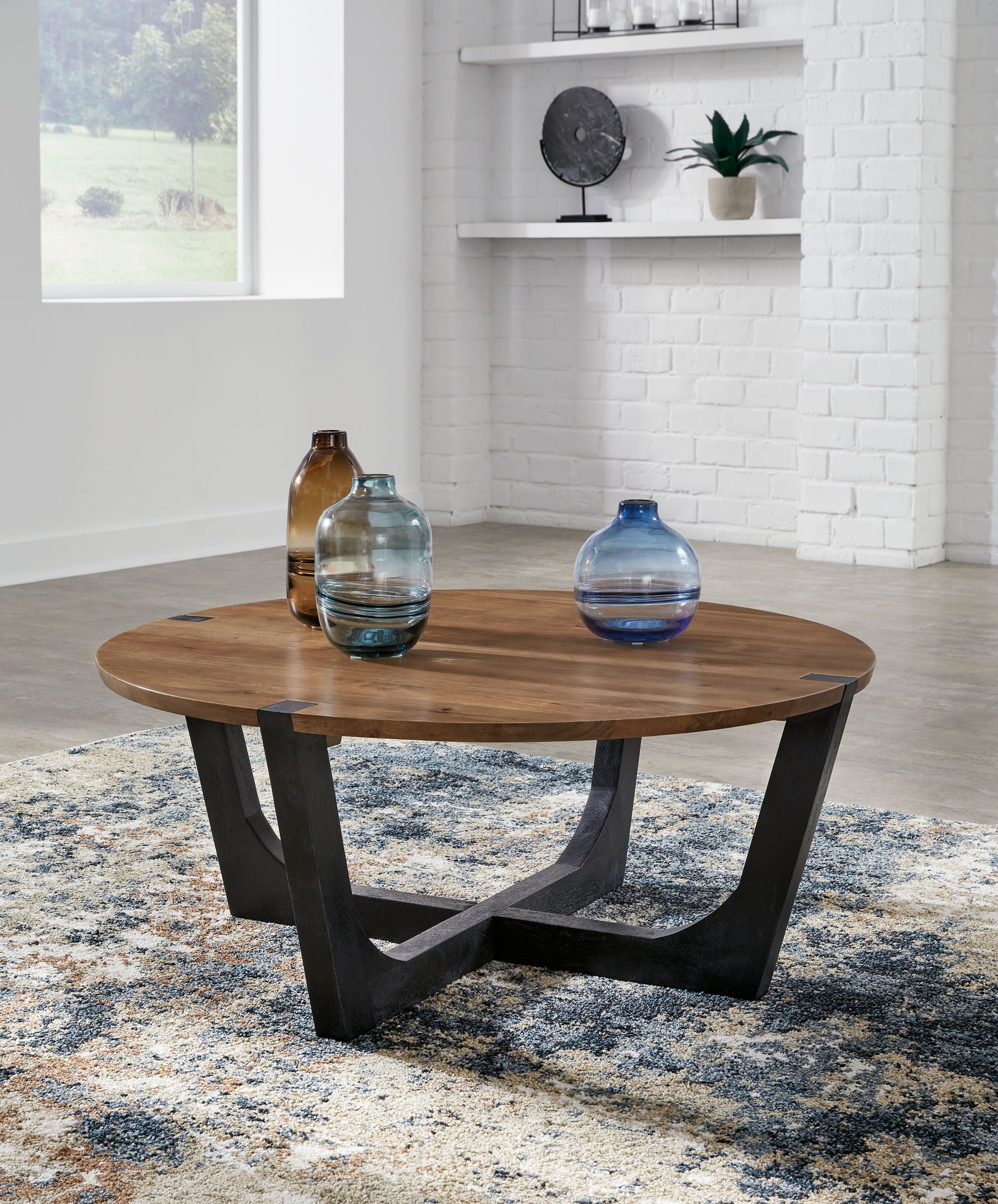 Round cocktail table with brown wood top and black metal base, bottles