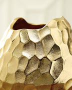 Gold hammered metal vase close-up showing faceted pattern and open rim