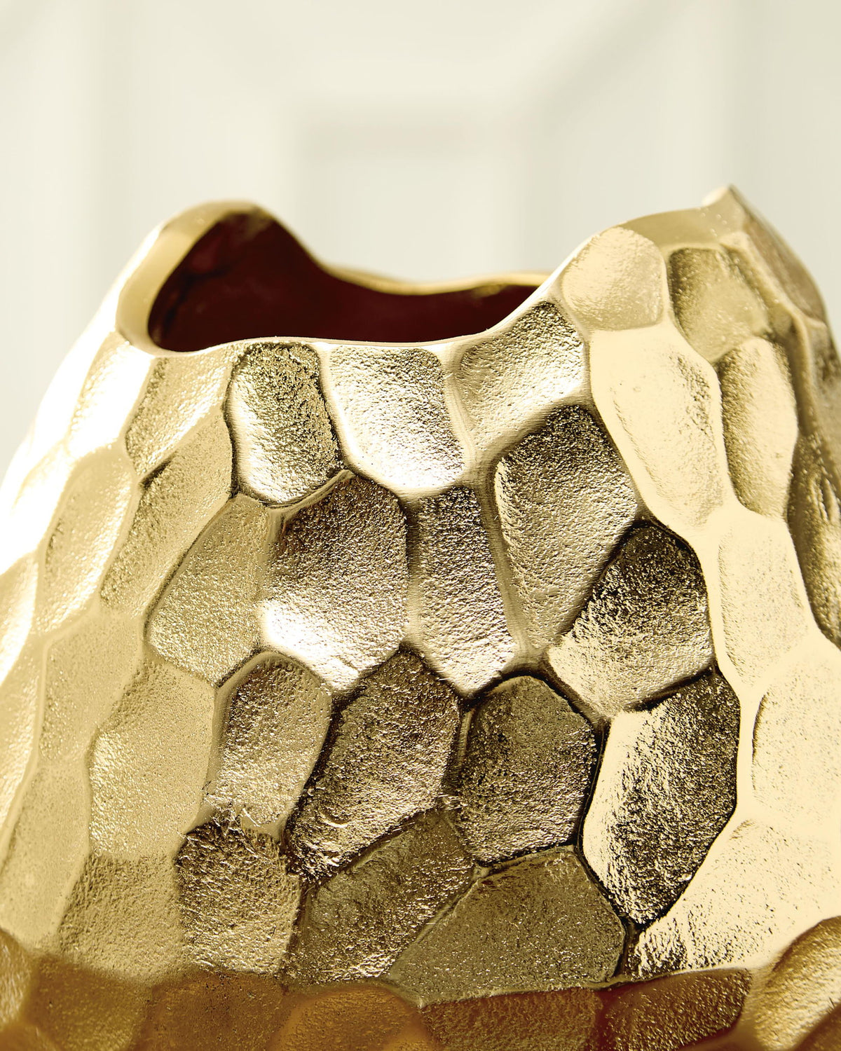 Gold hammered metal vase close-up showing faceted pattern and open rim