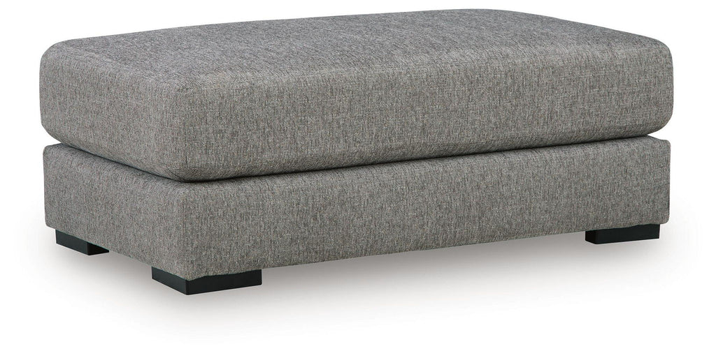 Grey upholstered oversized ottoman with wide cushioned top and tapered legs