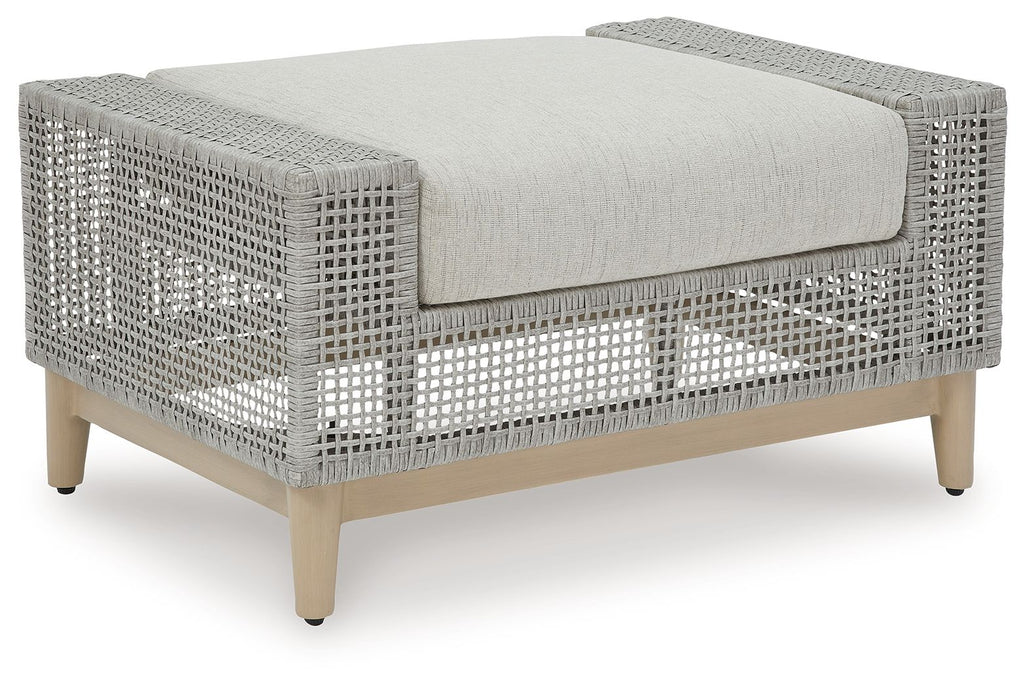 Gray outdoor ottoman with woven lattice sides and padded square cushion