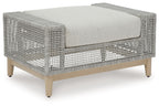 Gray outdoor ottoman with woven lattice sides and padded square cushion