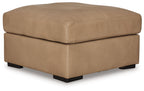 Light brown fabric ottoman with thick cushioned top and low black legs