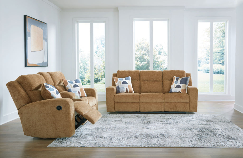 Light brown reclining sofa and matching recliner with blue patterned pillows