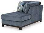 Navy chaise lounge with rounded arms, tufted back, and patterned throw pillow