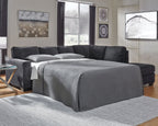 Dark gray sleeper sectional sofa with chaise, tufted back, and fitted bedding