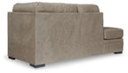 Beige corner chaise sofa shown from side, padded arms, three-seat base, dark legs.
