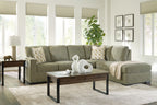 Moss green sectional sofa with chaise corner and patterned pillows on seats