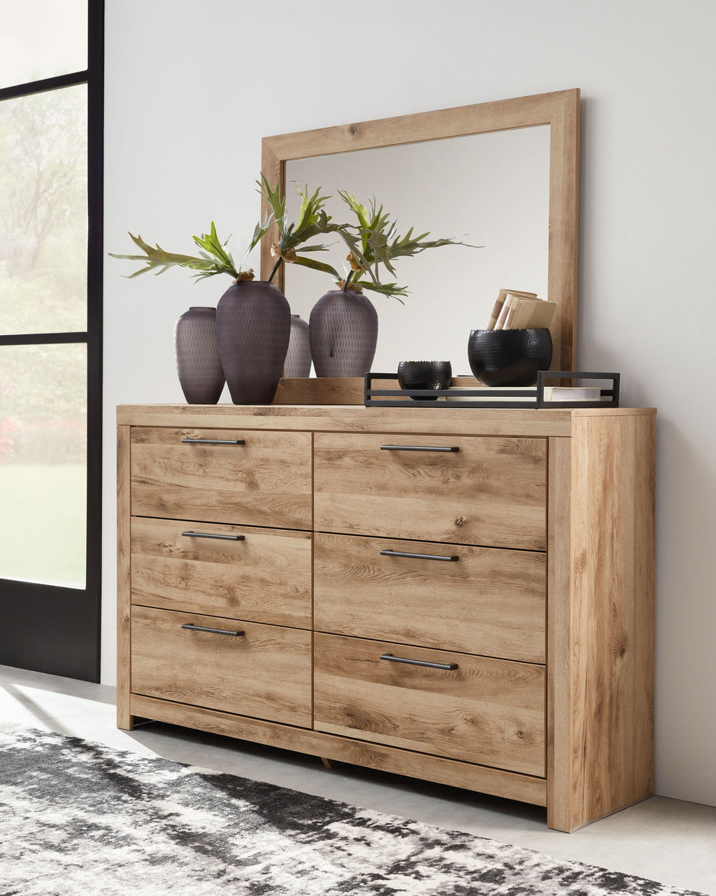 Tan wood dresser with framed mirror and six drawers, dark bar pulls