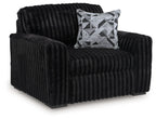 Black chair-and-a-half, ribbed upholstery, geometric throw pillow