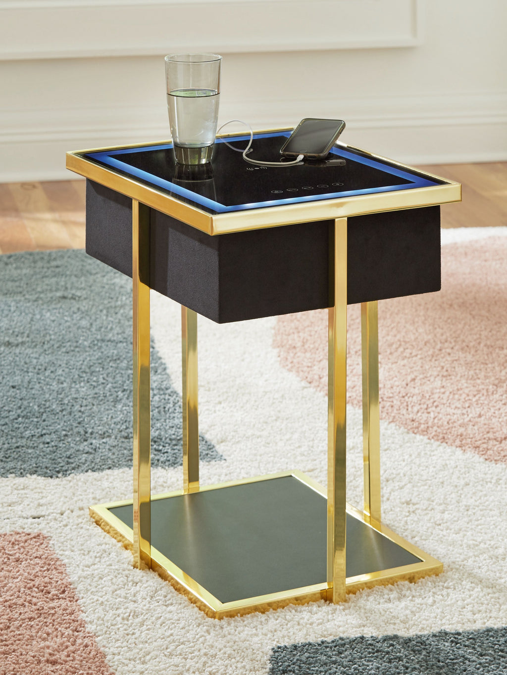 Black accent table with gold legs, blue-lit top panel, glass drink holder and lower shelf