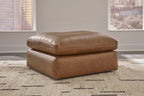 Light brown oversized accent ottoman with padded round top and two-tier seat base