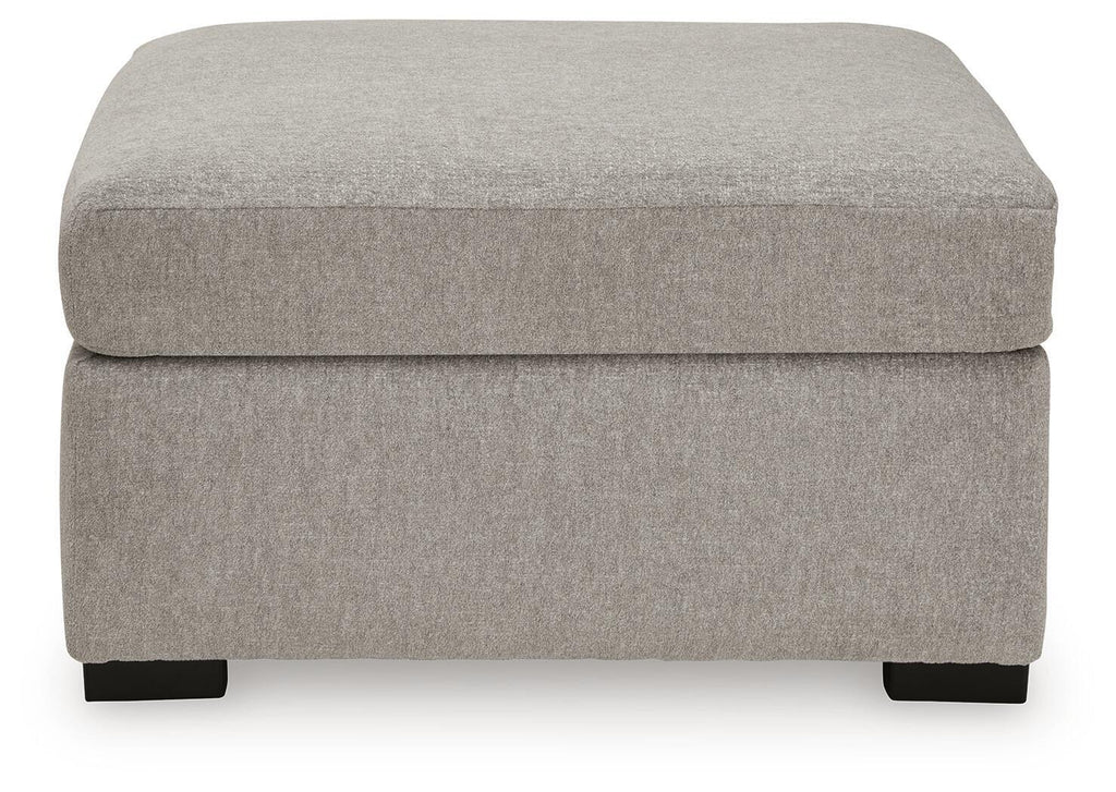 Upholstered ottoman in light gray fabric with cushioned top and dark wooden legs