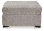Upholstered ottoman in light gray fabric with cushioned top and dark wooden legs