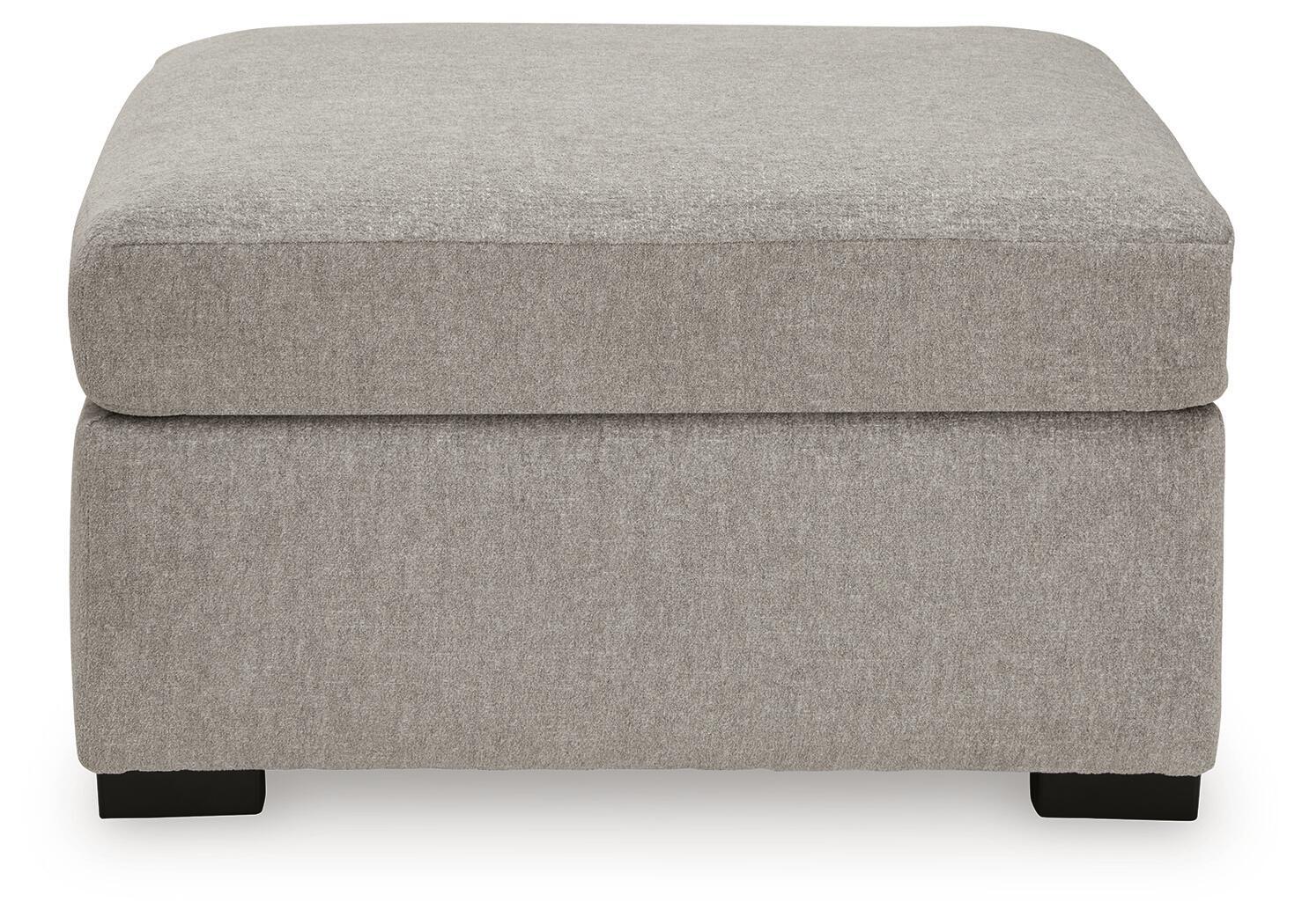 Upholstered ottoman in light gray fabric with cushioned top and dark wooden legs