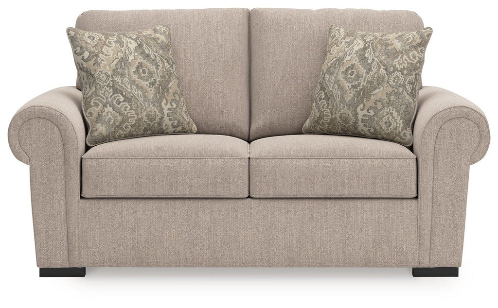 Beige loveseat front view with rolled arms, two back pillows, and patterned cushions