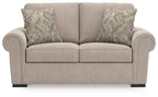 Beige loveseat front view with rolled arms, two back pillows, and patterned cushions