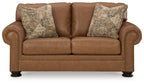 Caramel loveseat with two patterned pillows and tufted arm panels