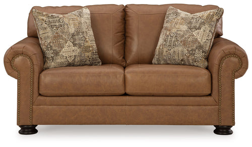 Caramel loveseat with two patterned pillows and tufted arm panels