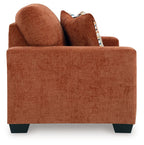 Rust orange loveseat with two decorative patterned throw pillows and rounded arms.